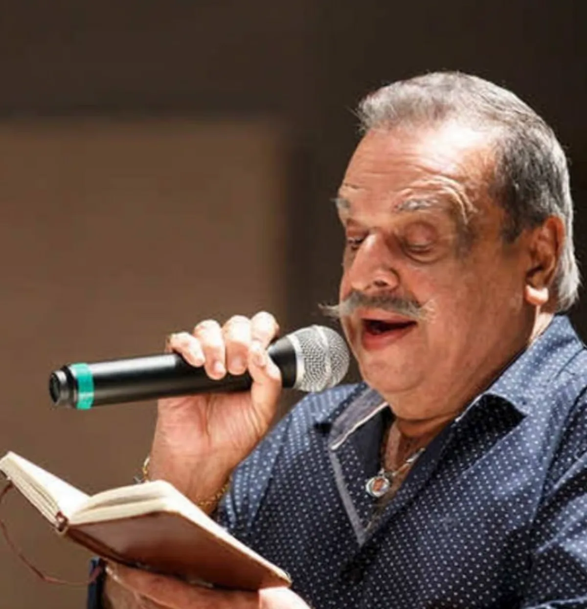 P. Jayachandran performing live on stage holding a microphone